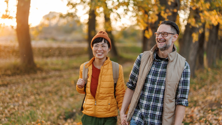 Happy couple holding hands while enjoying relaxing walk in autumn nature