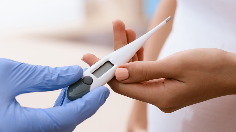 A thermometer being handed to someone