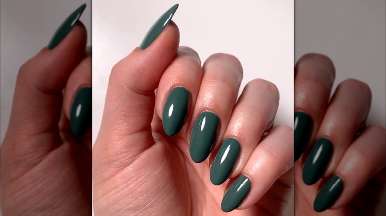 A cool toned hand wearing a green cool toned green nail polish