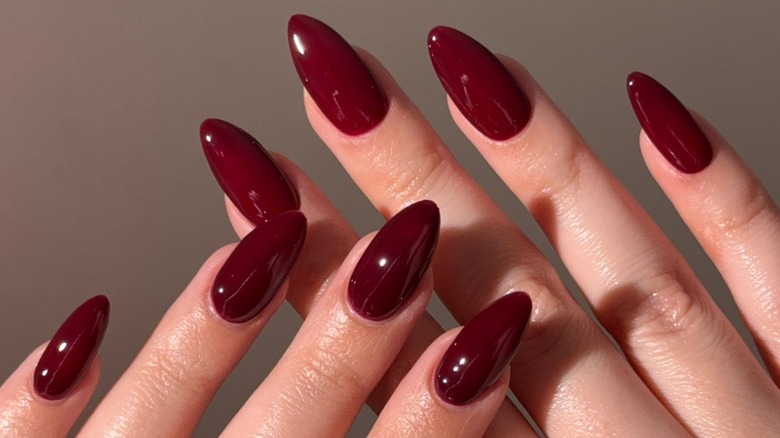 Two hands with long nails and a cherry red manicure