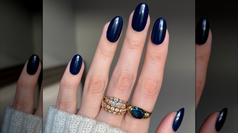 A cool skin toned hand with a dark navy manicure