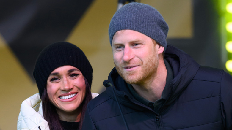 Prince Harry and Meghan Markle smiling and wearing winter hats
