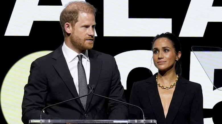 Prince Harry and Meghan Markle at a podium and wearing black