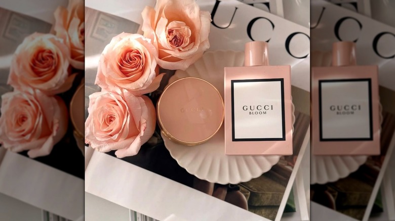 Gucci Bloom fragrance in flat lay alongside flowers and compact mirror