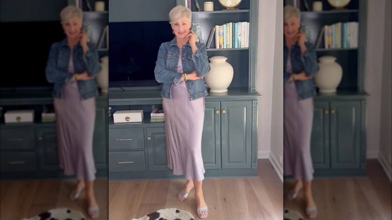 A woman wearing a purple satin slip dress with a denim jacket