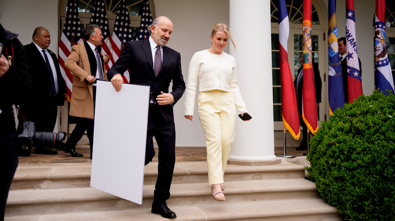 Karoline Leavitt at the White House with a man carrying a board