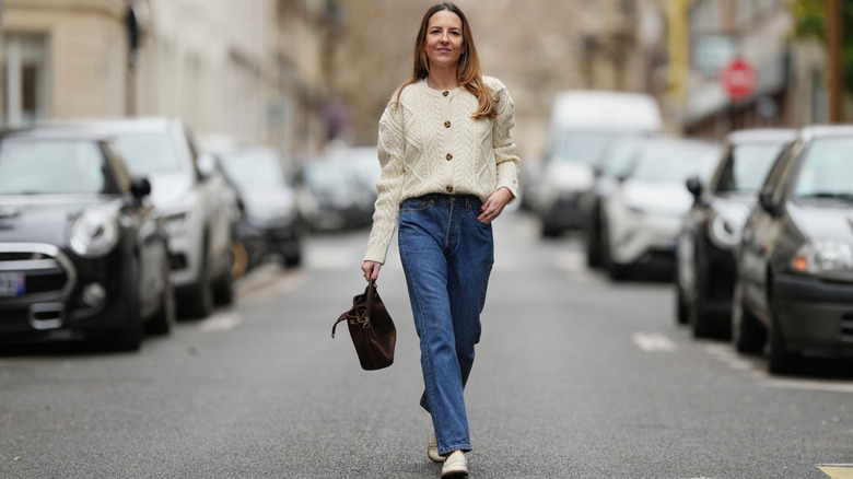 Style influencer Alba Garavito Torre poses for a photo in a casual warm weather outfit with loose straight-leg jeans and a white button-up cardigan