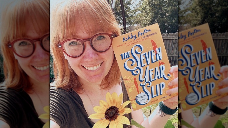 Ashley Poston smiling for a selfie while holding up "The Seven Year Slip"