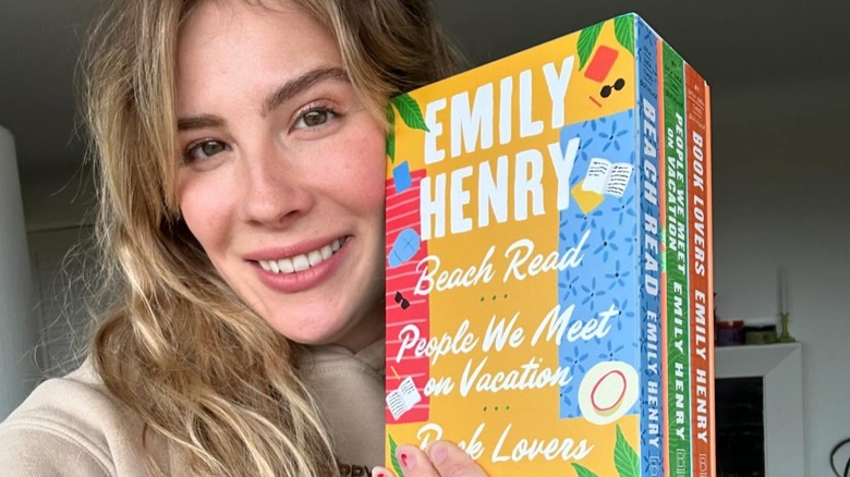 Selfie of Emily Henry holding a box set of three of her books