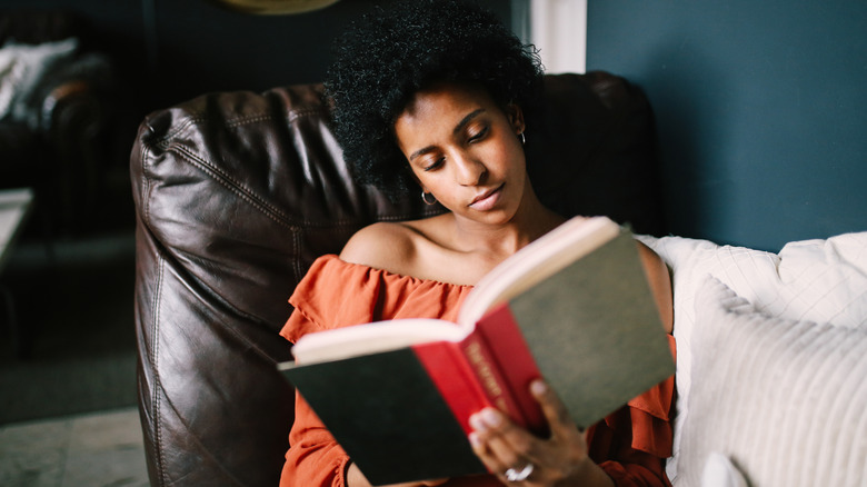 Young woman relaxing on the bed reading a book
