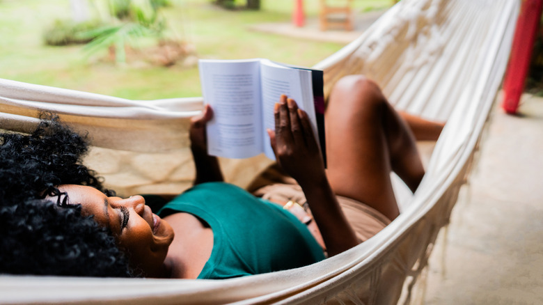 Woman reading a book on hammock outdoors