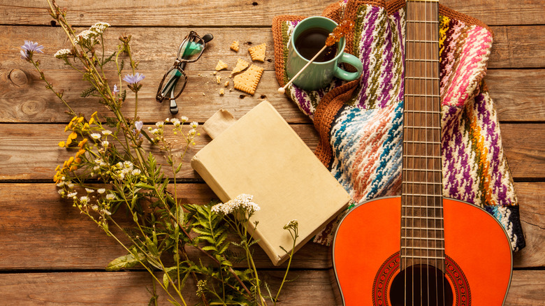 Book surrounded by flowers, guitar, and coffee cup