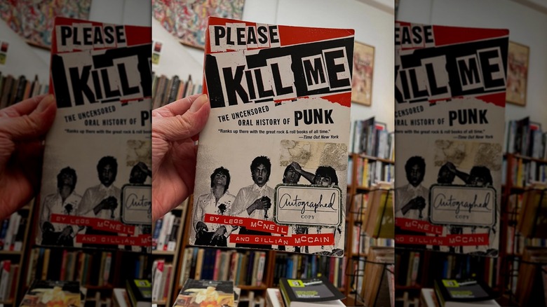 A hand holding up a copy of "Please Kill Me" in a bookstore