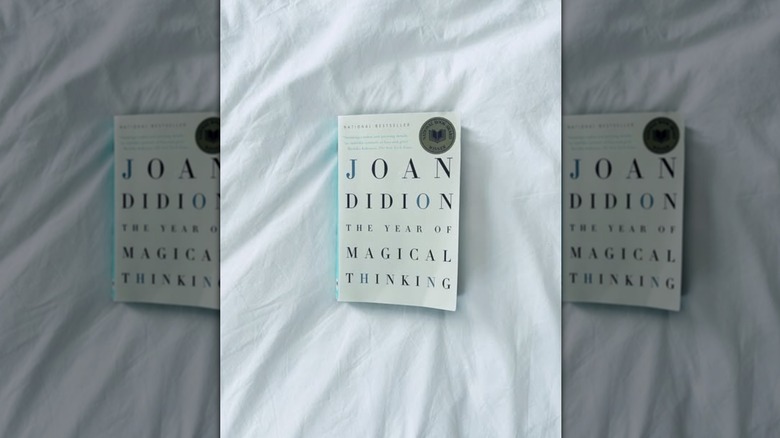 A copy of "The Year of Magical Thinking" laying on a white bedspread