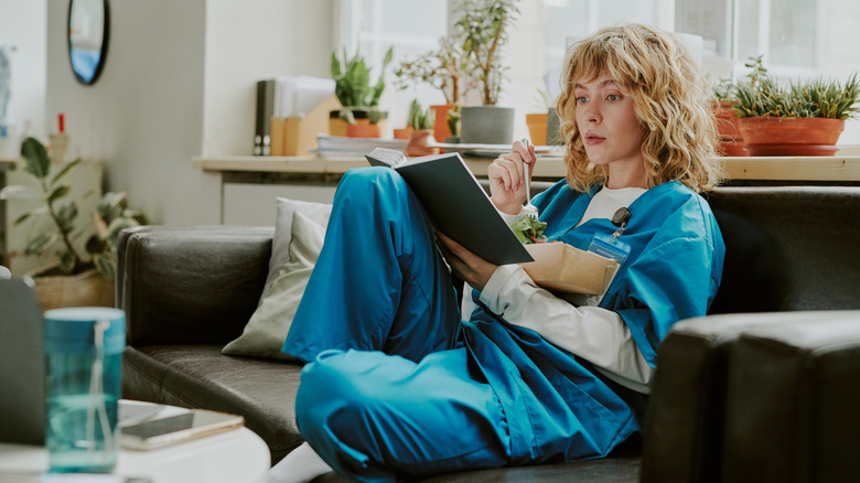 Woman in scrubs reading a book