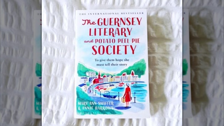 A copy of the book "The Guernsey Literary and Potato Peel Pie Society" laying on a white blanket