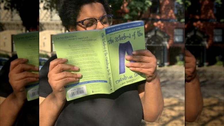 A woman reading a copy of "The Sisterhood of the Traveling Pants"