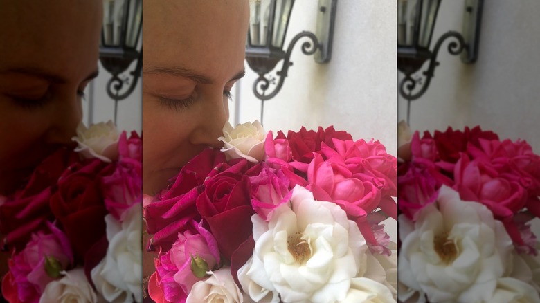 Close-up of Nicole Kidman smelling a bouquet of pink, red, and white roses