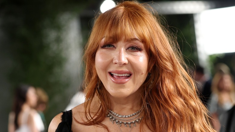 Charlotte Tilbury smiling in front of a blurred background with her hair over her left shoulder