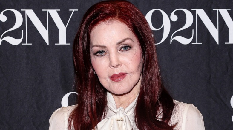 Priscilla Presley on the red carpet posing in front of a dark background