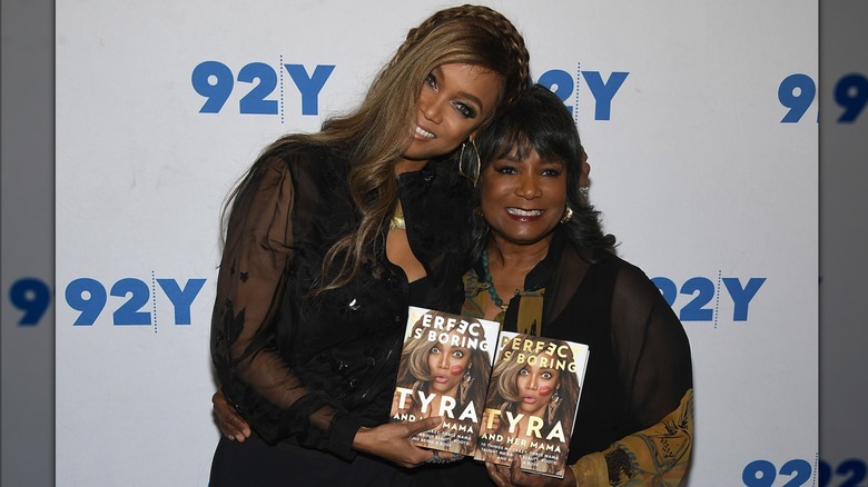 Tyra Banks and her mom posing with copies of their book "Perfect Is Boring"