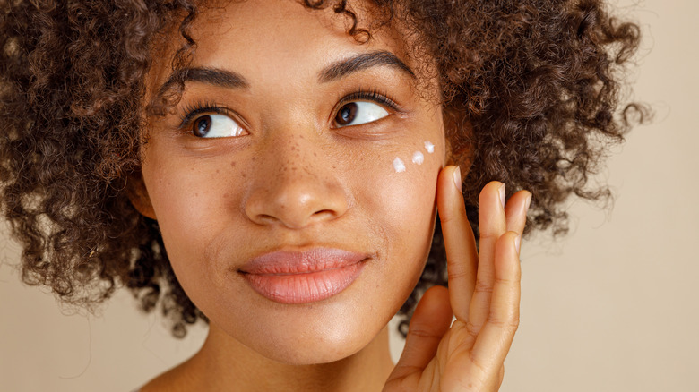 Woman putting cream on her face 