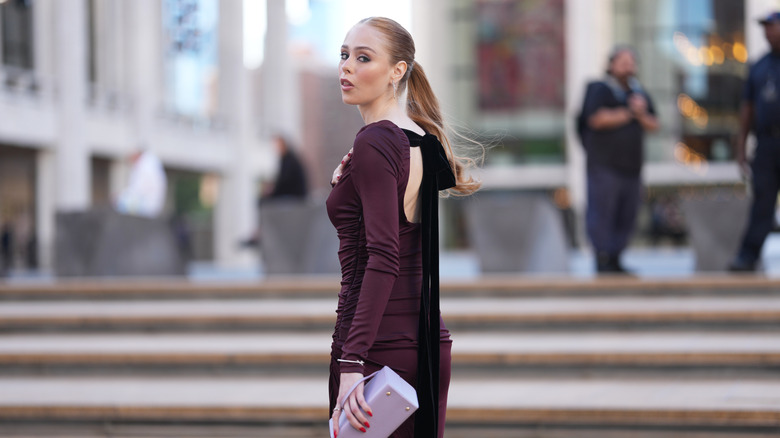 A redheaded woman wearing a plum dress