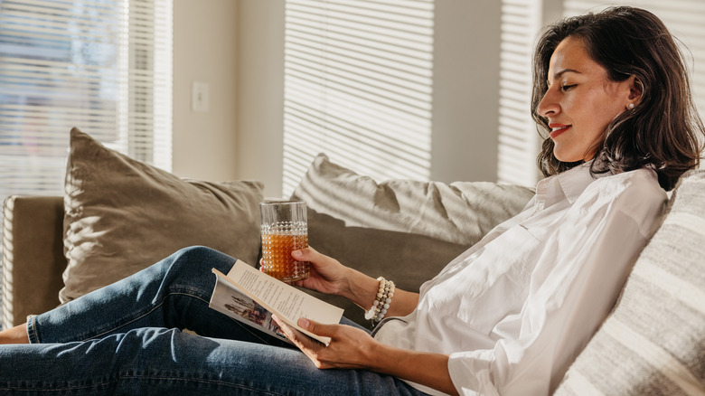 Woman enjoying a day off and reading a book on the couch in their home