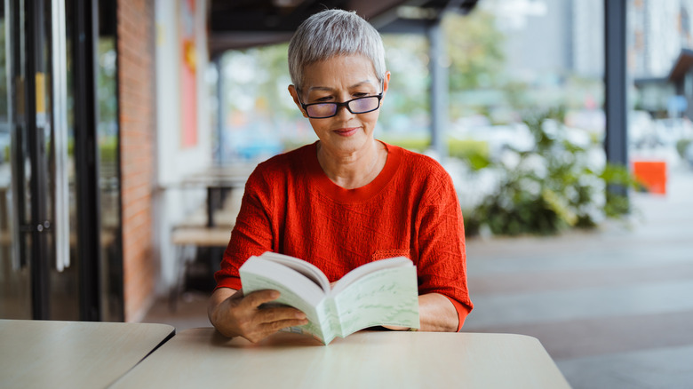 Mature woman reading book in cafe