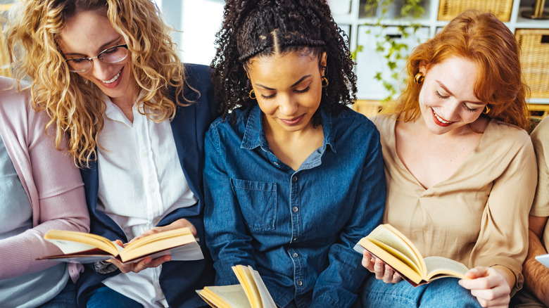 Trio of women sitting together and reading open books