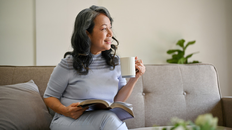 A happy and relaxed retired Asian woman is looking out the window and daydreaming