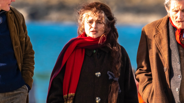 Helena Bonham Carter on the beach with long braided hair and a red scarf