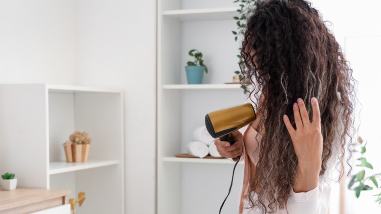 A woman blow-drying her curly hair