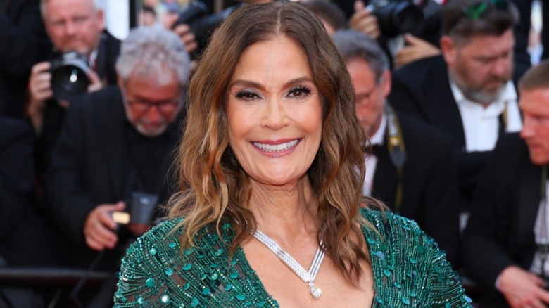 Teri Hatcher smiling in a green dress while posing on the red carpet