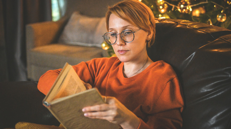 Woman reading a book in front of a Christmas tree