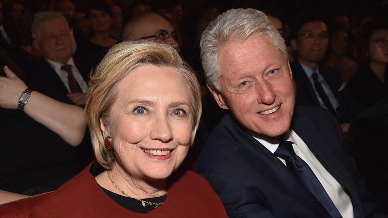 Bill Clinton and Hillary Clinton sitting together, smiling for a photo