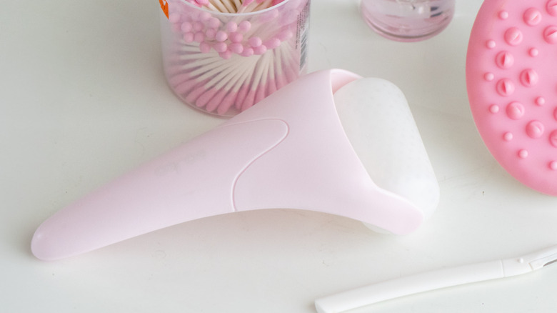 Pink ice roller on a table beside other pink beauty tools