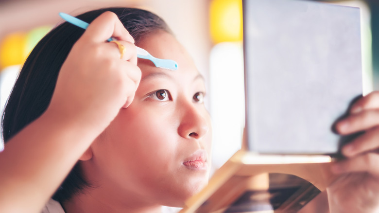 A young woman dermaplaning her face