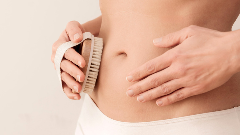 A woman dry brushing her stomach