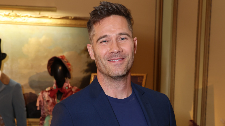 Luke Mcfarlane smiling at the camera and wearing a blue suit and shirt