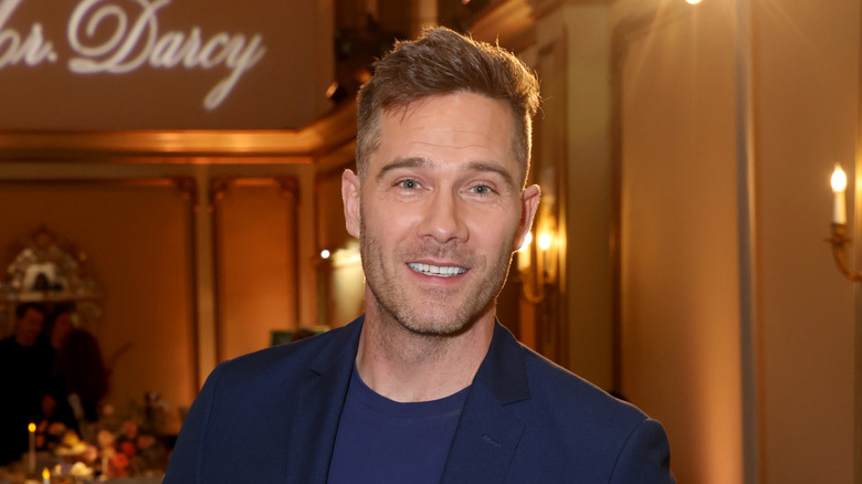 Luke Macfarlane smiling at the camera in a ballroom
