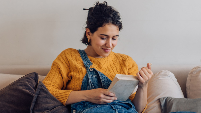 Woman wearing overalls reading a book