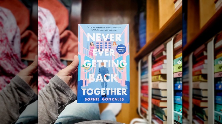 A hand holding "Never Ever Getting Back Together" with the floor beneath