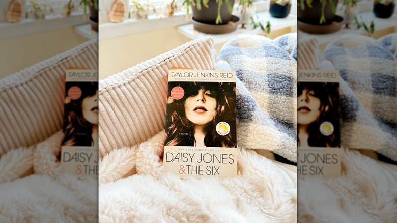 A copy of "Daisy Jones & the Six" laying against some throw pillows