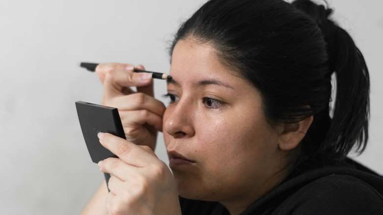 older women looking forward into small mirror wearing a black shirt