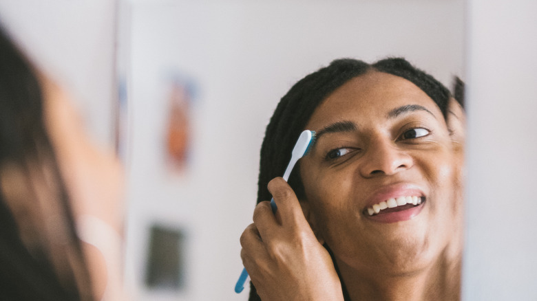 women looking forward brushing brows at the end with toothbrush