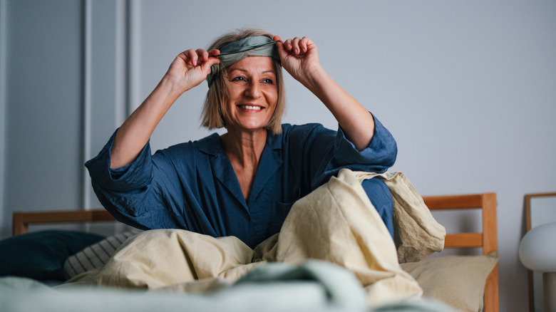 A woman with a bob in bed with a blue night shirt on