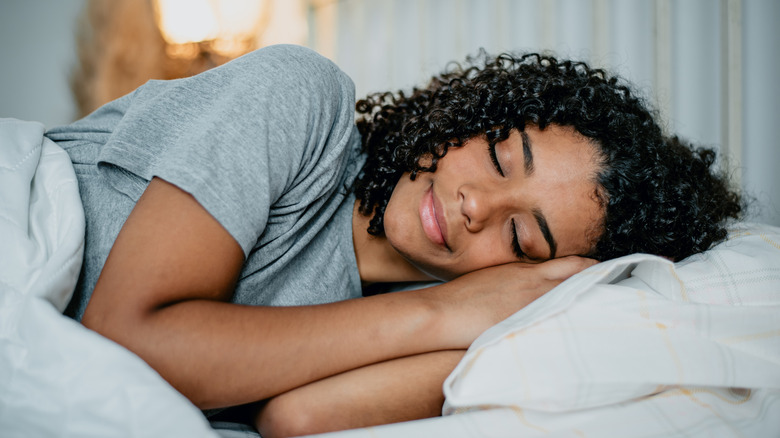 A woman with curly hair sleeping in bed