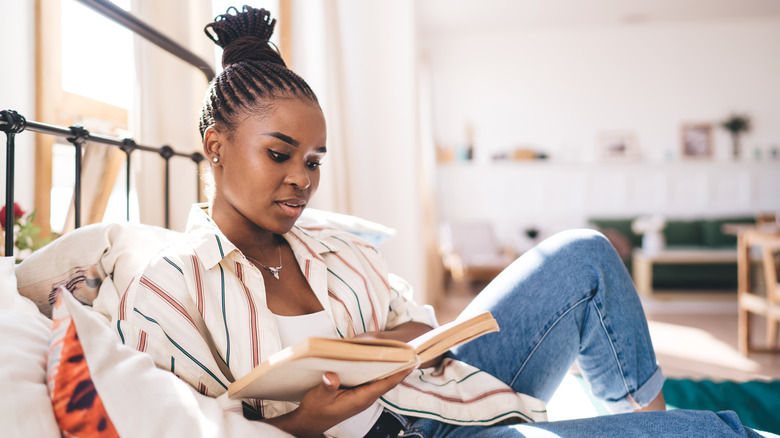 A woman sitting on a bed reading a book