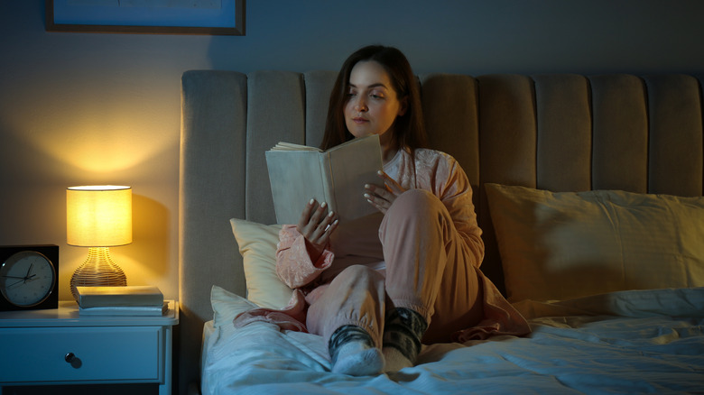 Woman reading at night on her bed
